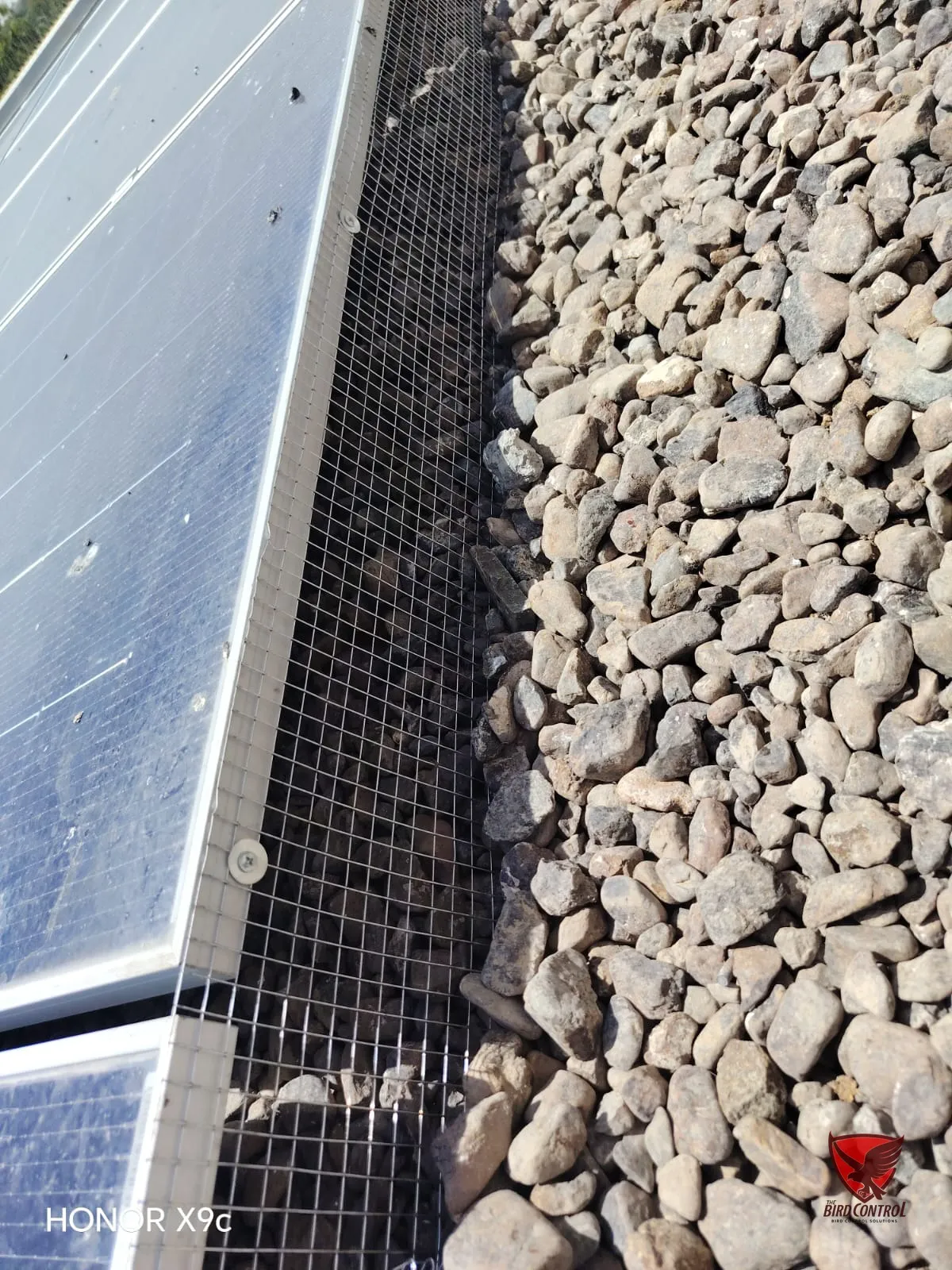 Close-up of wire mesh sealing gap beneath solar panels to stop nesting